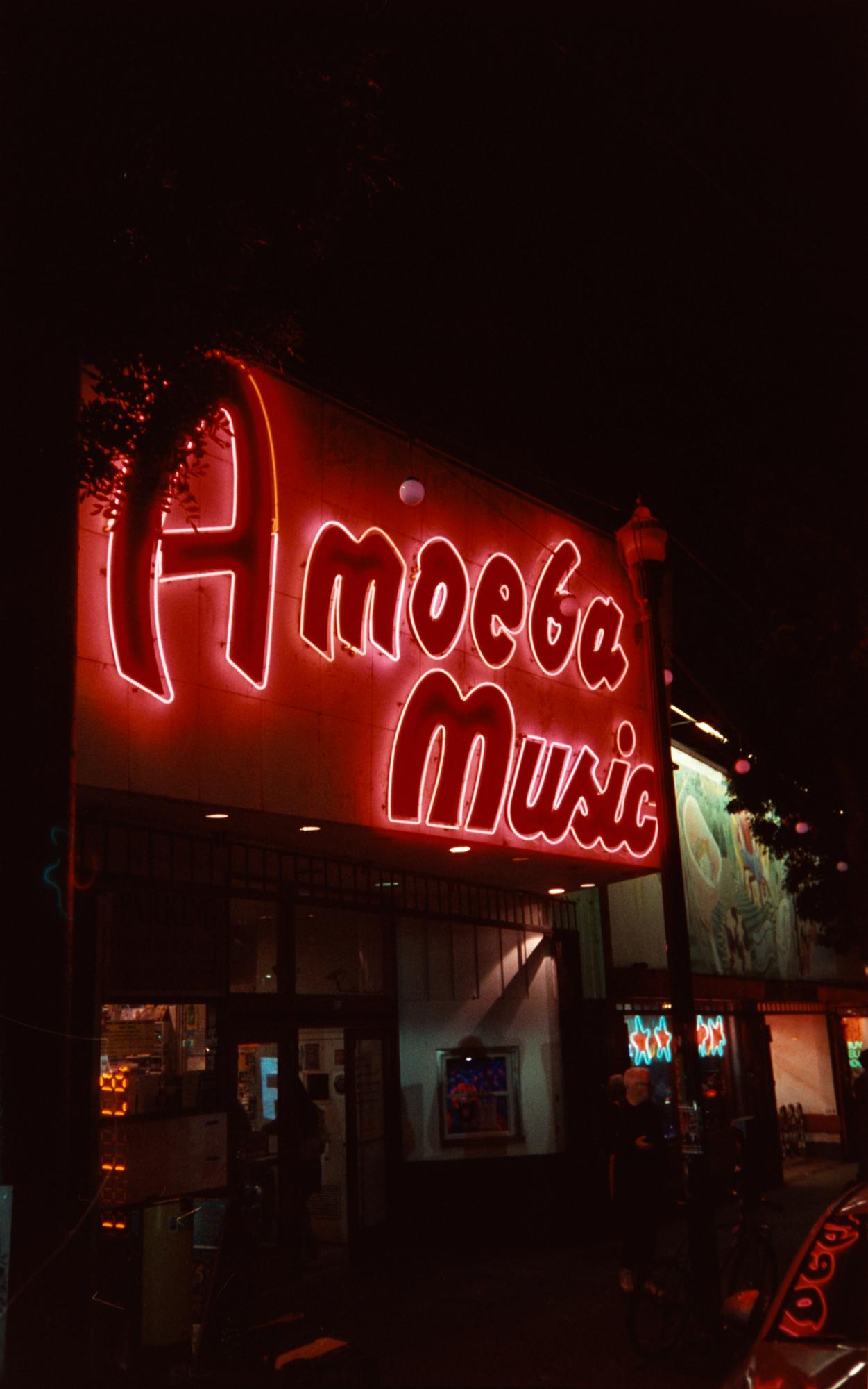 The red neon Amoeba Music sign glowing above the store entrance at night in San Francisco
